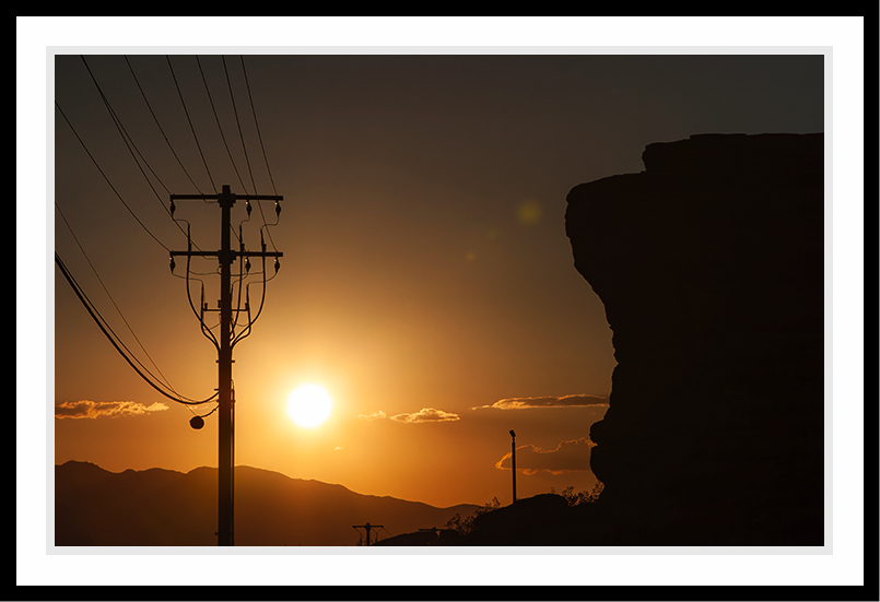 A telephone pole and a mountain cliff at daybreak.